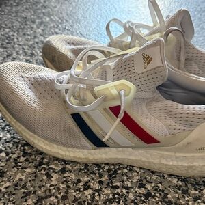 White Athletic adidas boost sneakers . The are worn .